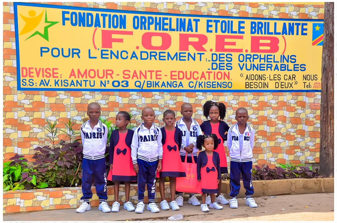 Enfants de la fondation rassemblés devant la pancarte de l'orphelinat